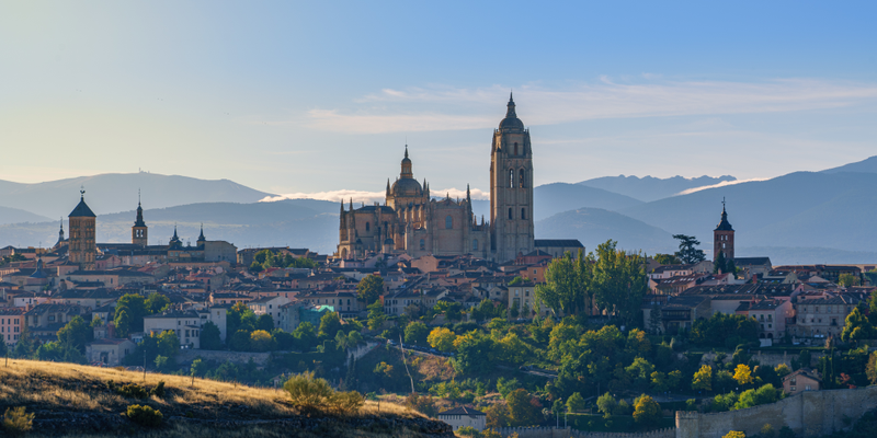 Hilltop town at sunrise with a large cathedral tower above terracotta roofs and green trees — The Spain Move Kit